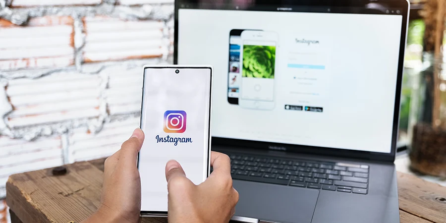 Celular com Instagram ao lado de um notebook com um site próprio